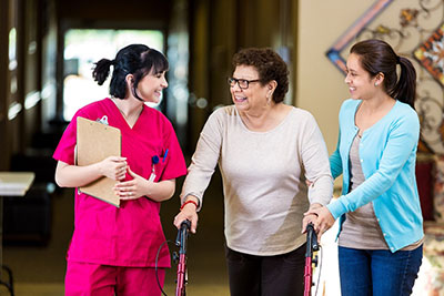 female caregiver walking with daughter and elderly mother